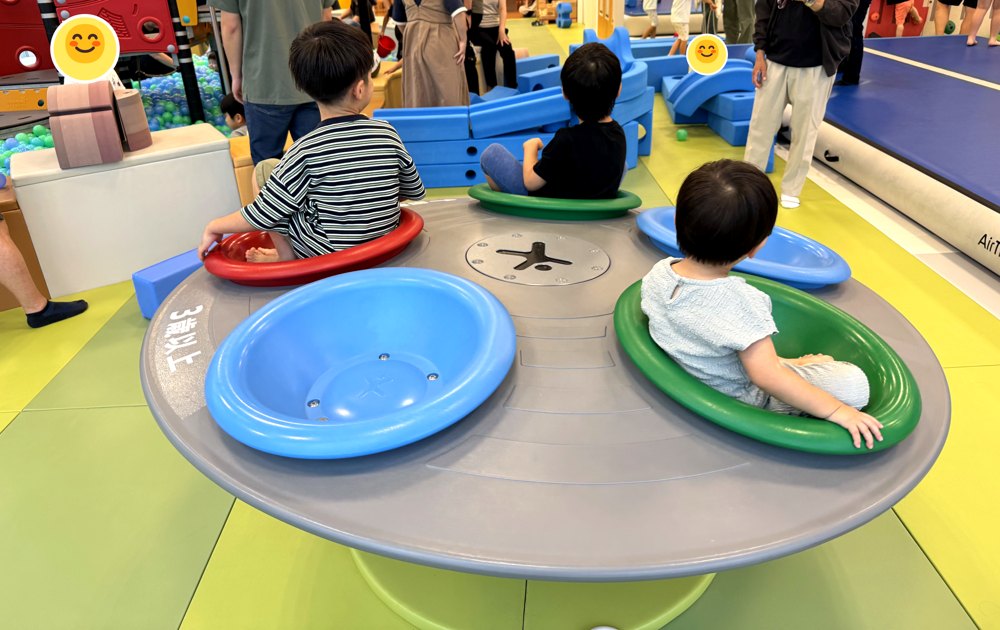 座席が並んだ円形の回転遊具に、子どもたちが座って回っている