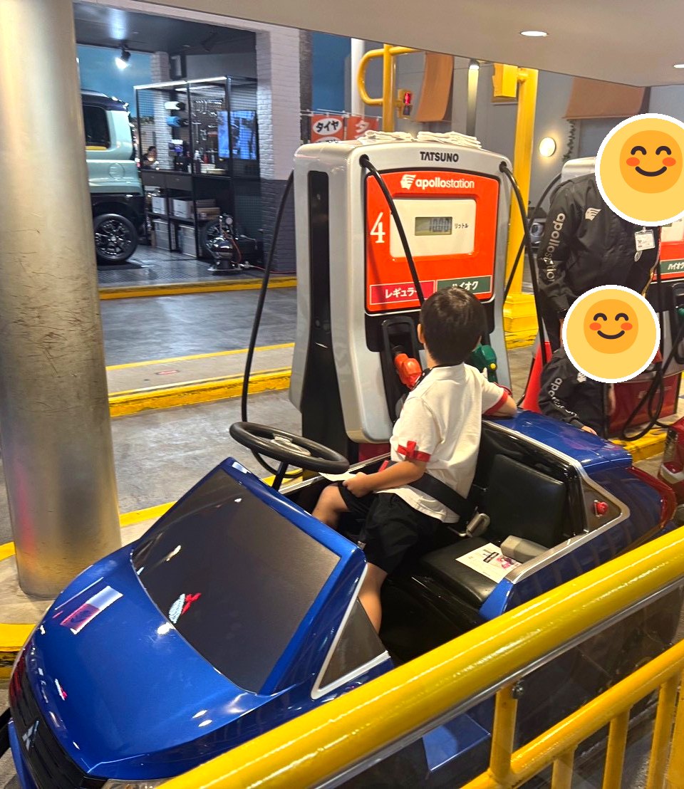 キッザニア東京のガソリンスタンド。子どもが運転する青い車に、店員役の子どもが給油している